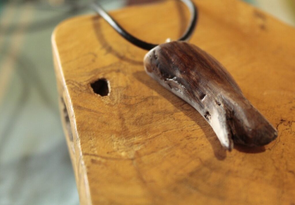 Pendentif en bois brun aux arêtes vives, sur cordon noir